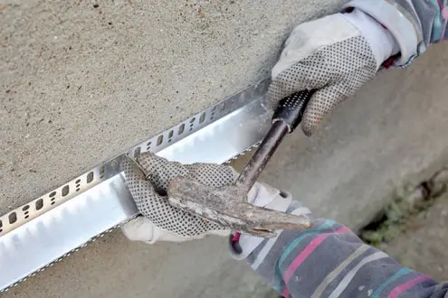 Worker installing metal corner bead during stucco wall repair in Reno, NV.